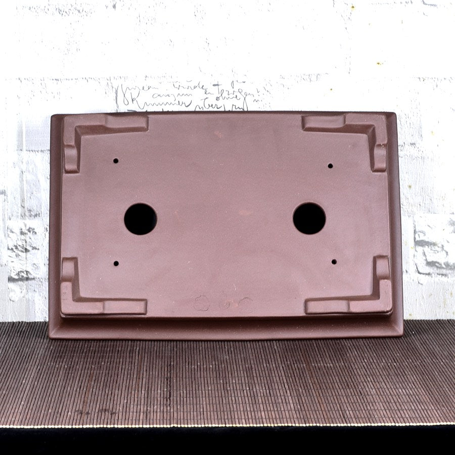 Underside of brown rectangular bonsai pot with corner feet and two large holes