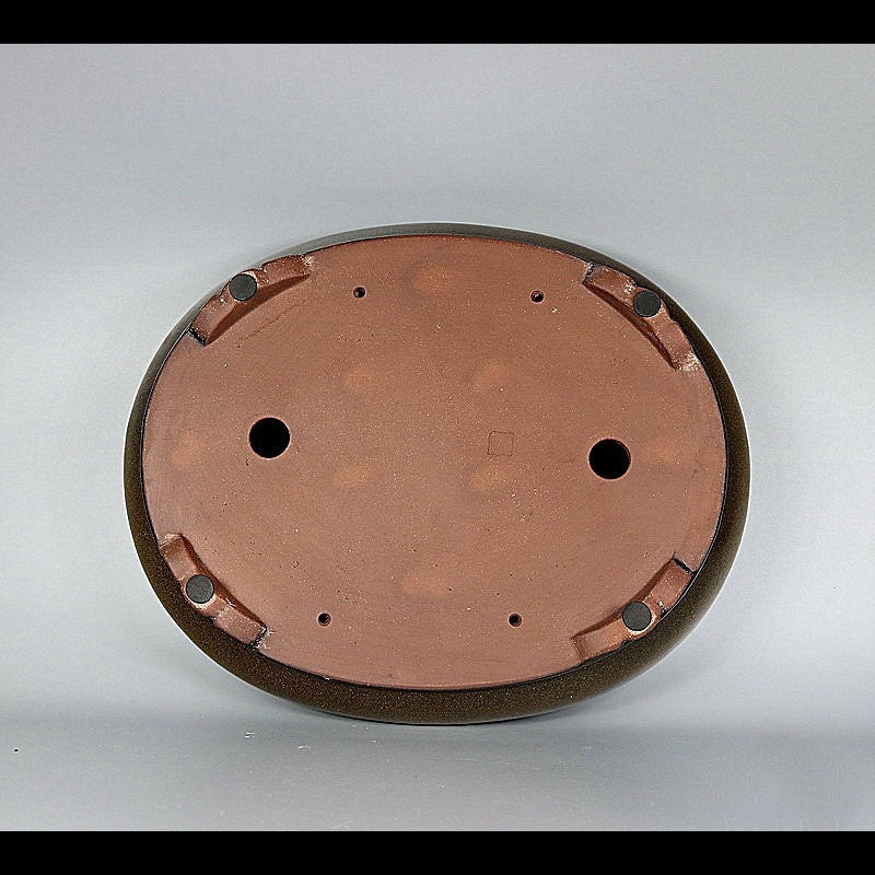 Underside of glazed oval pot showing two large openings and corner feet
