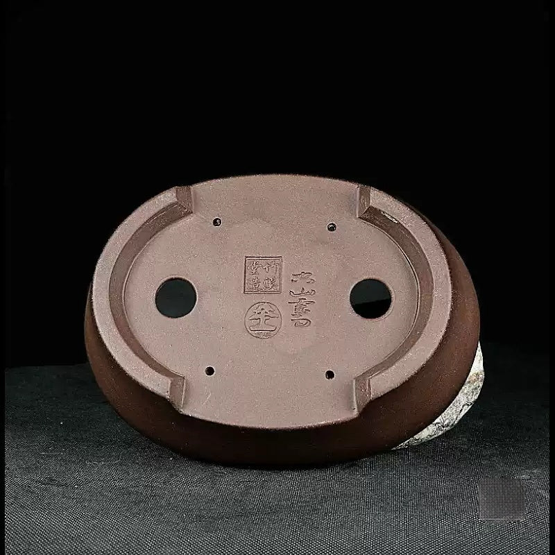 Underside of the oval pot showing drainage holes and impressed marks