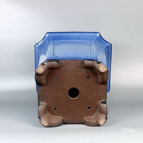 Underside of blue square pot showing central opening and four corner feet