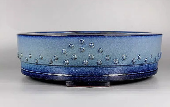 Front view of the light blue drum pot on a pale surface