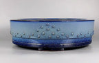 Front view of the light blue drum pot on a pale surface