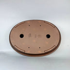 Underside of brown oval pot showing two large openings, feet and stamped marks