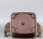 Underside of brown square pot showing large central opening and corner feet