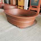 Angled brown oval pot showing double bands and curled feet