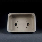 Interior of gray-brown rectangular pot showing two large openings and four small holes