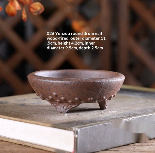 Small brown round bonsai pot with raised studs and sculpted feet, with dimensions above