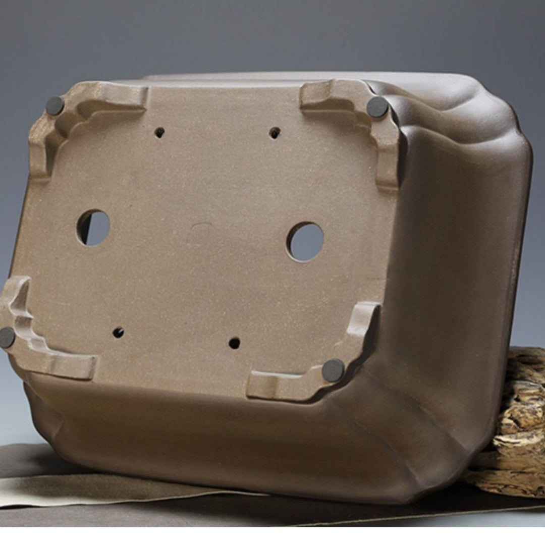 Underside of taupe rectangular pot with two large openings and four small holes