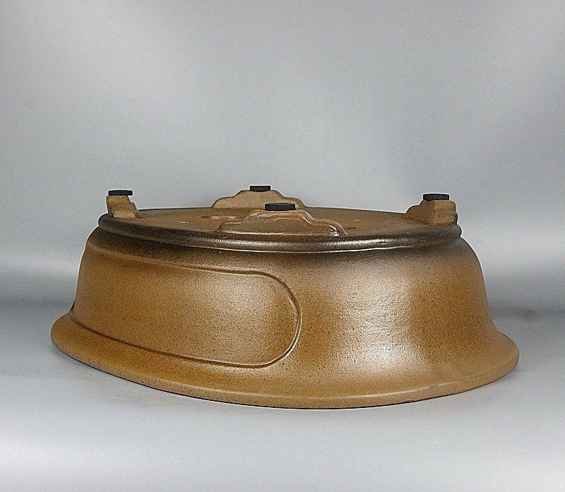 Upside-down ochre oval pot showing side panel and feet