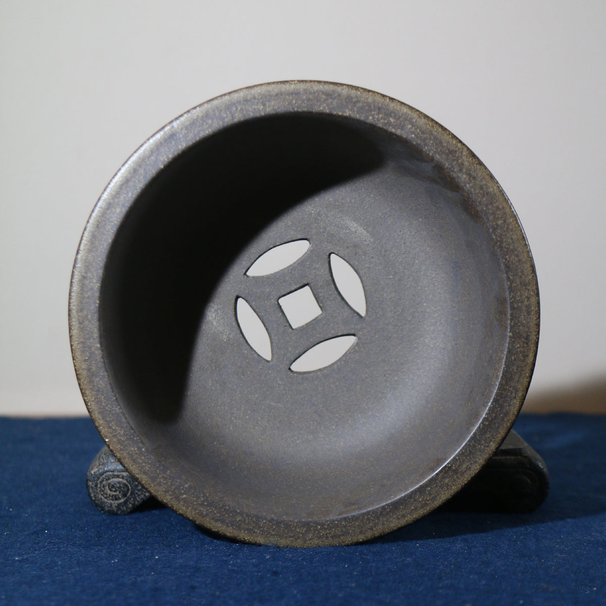 Interior of the dark pot with square center opening and four oval drainage slots