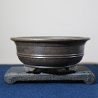 Front view of the dark pot on its stone stand