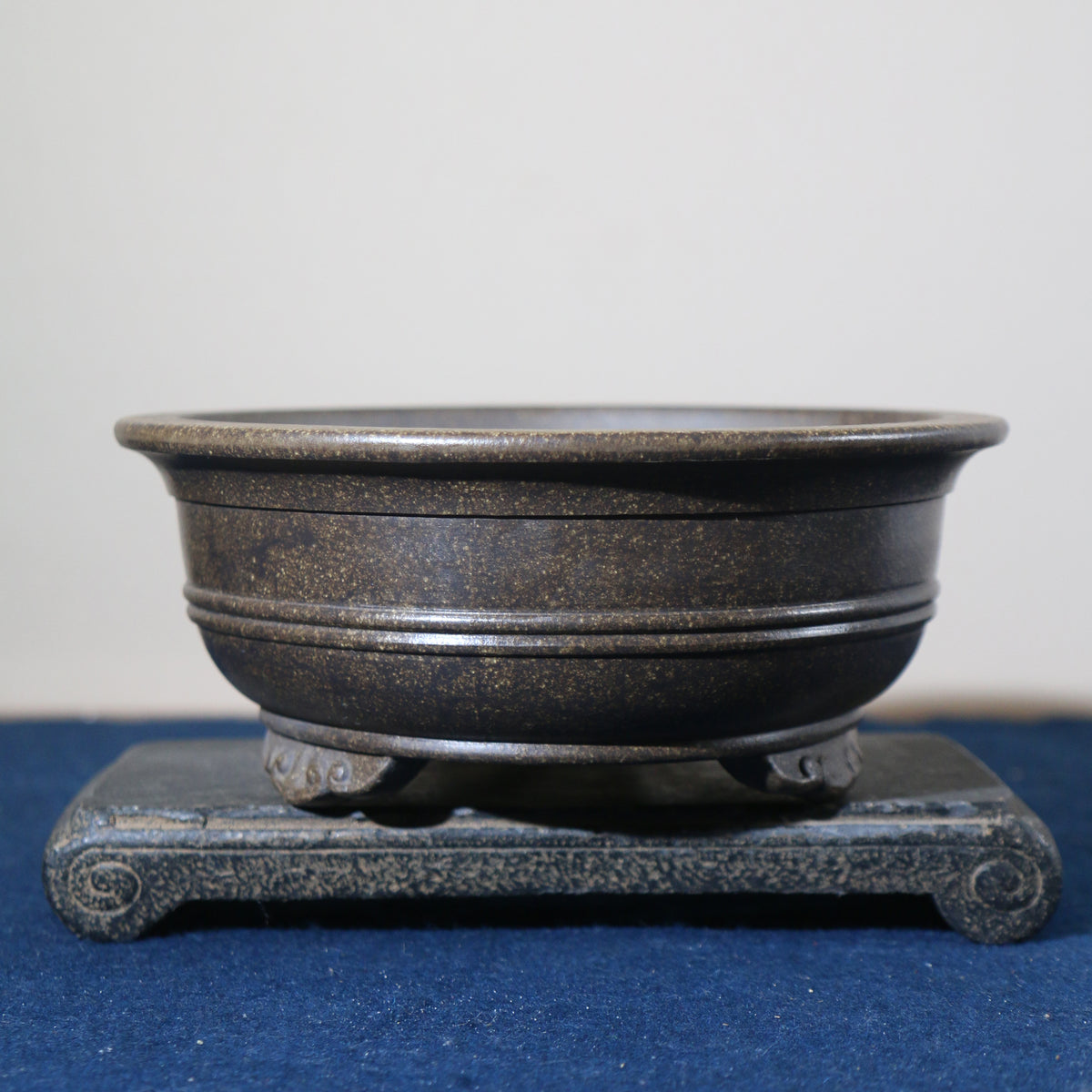 Front view of the dark pot on its stone stand