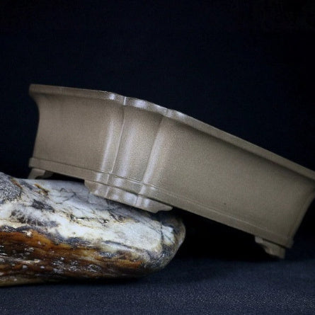 Taupe rounded rectangular pot tilted on stone showing curved sides