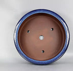 Interior of the blue pot showing brown clay and four drainage openings