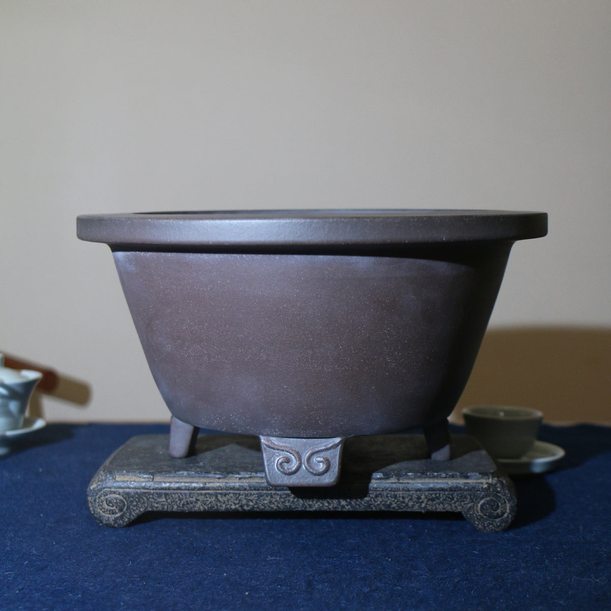 Front view of the deep round brown pot on a rectangular stand