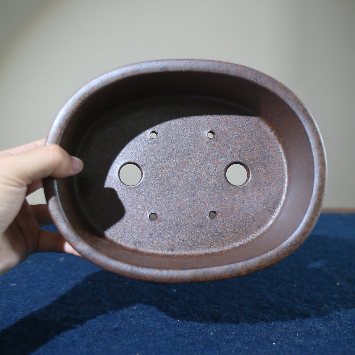 Top view of brown oval pot showing two large openings and four small holes