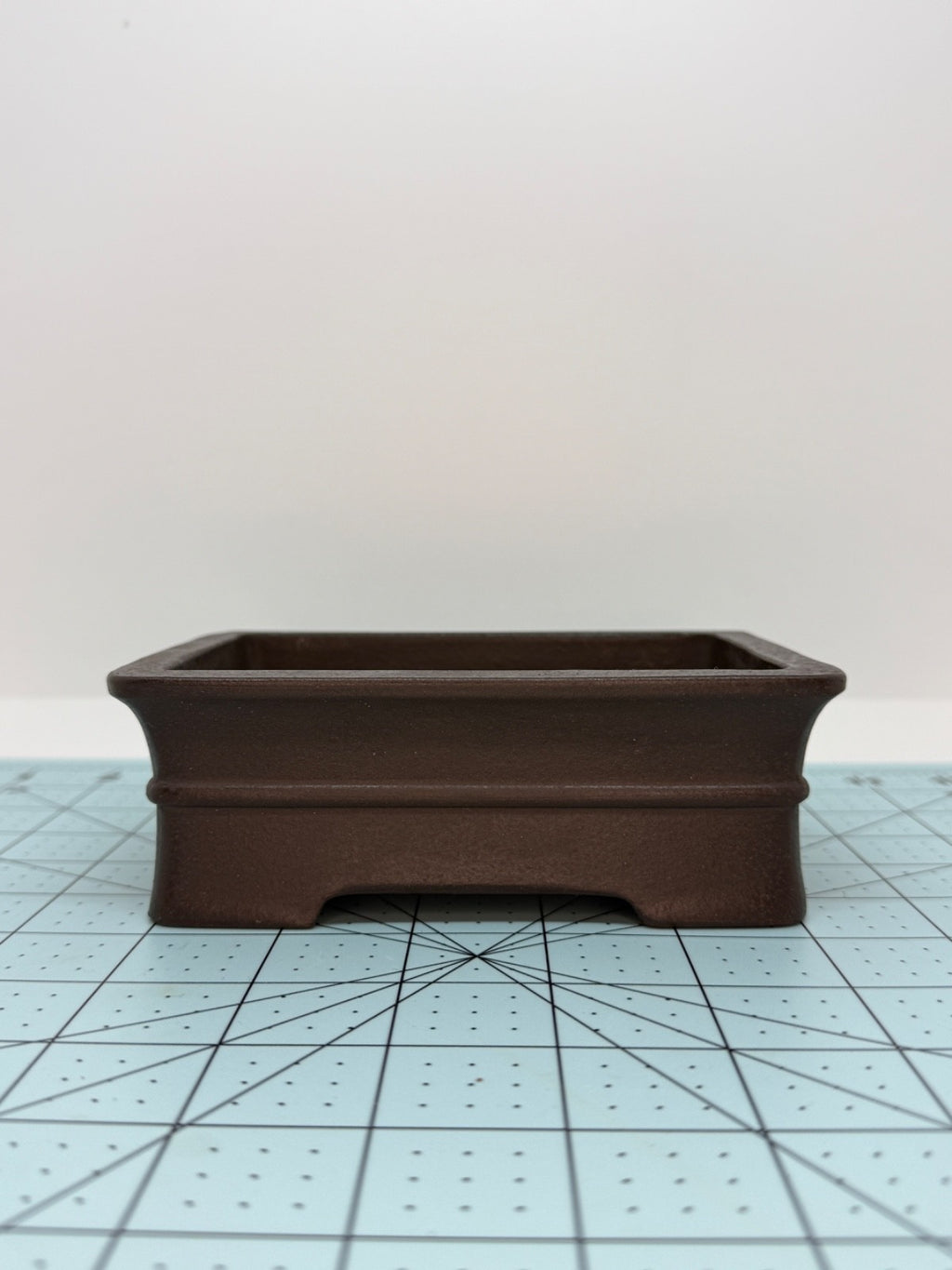 Long-side view of the dark brown rectangular pot with flared rim and low feet