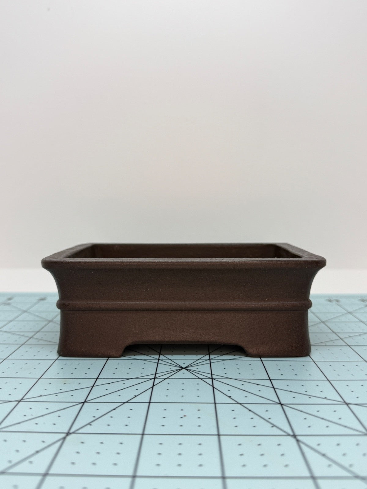 Long-side view of the dark brown rectangular pot with flared rim and low feet