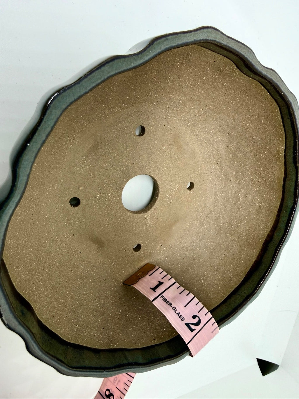 Interior of the fluted pot with a tape measure, central drainage hole and four smaller openings