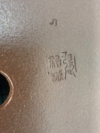 Close-up of impressed marks beside a drainage hole in the brown pot's base