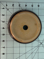 Underside of the round pot showing a pale base and one central drainage hole