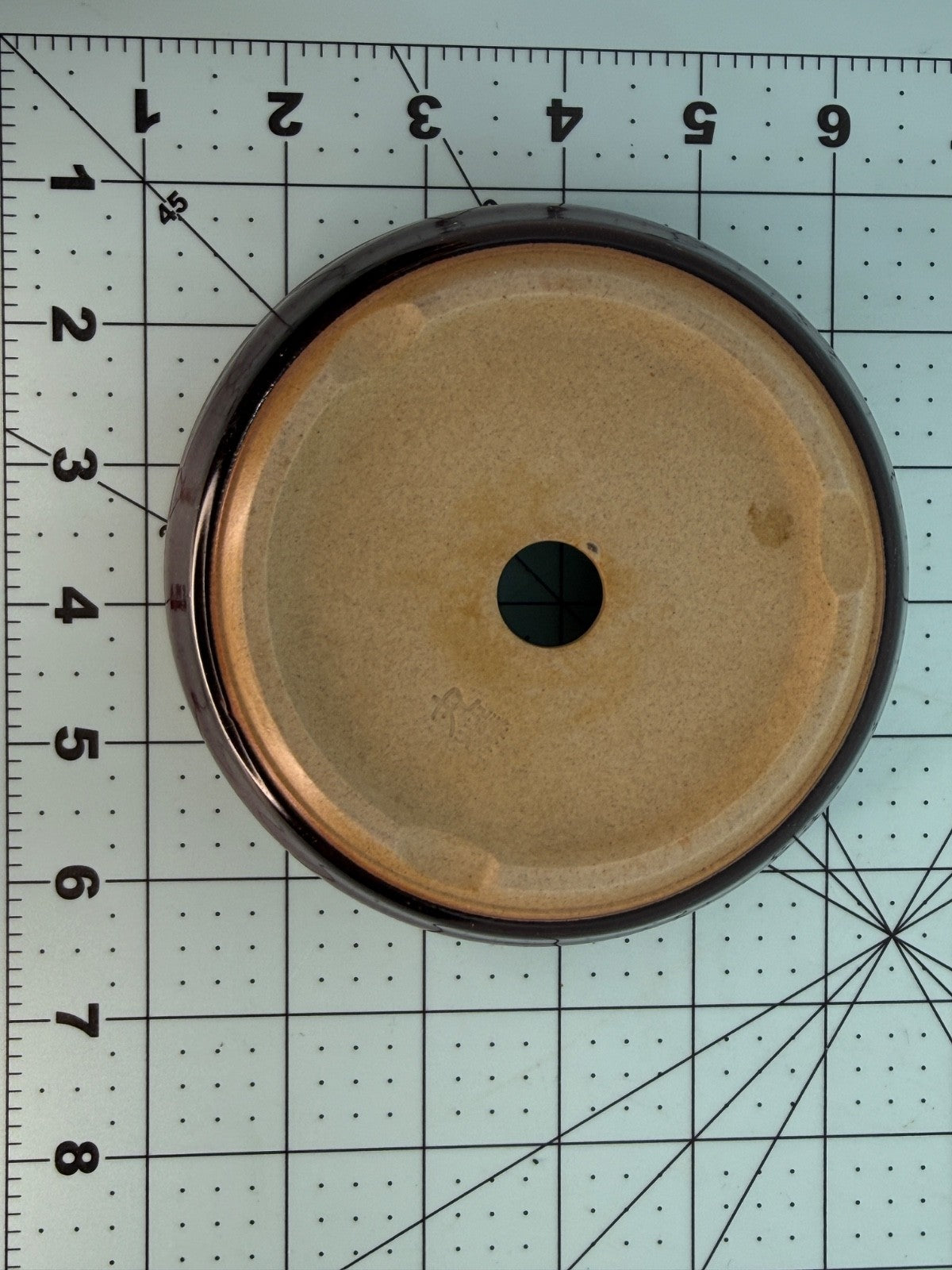 Underside of the round pot showing a pale base and one central drainage hole