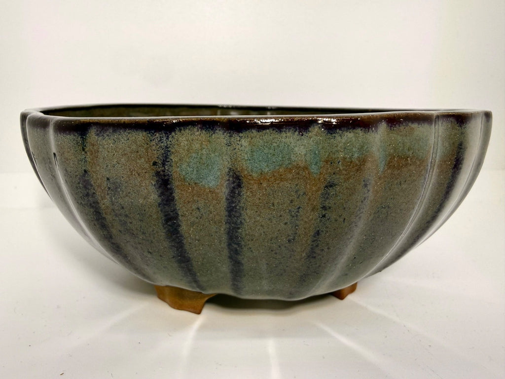 Front view of the green-gray round pot showing dark vertical accents and short feet
