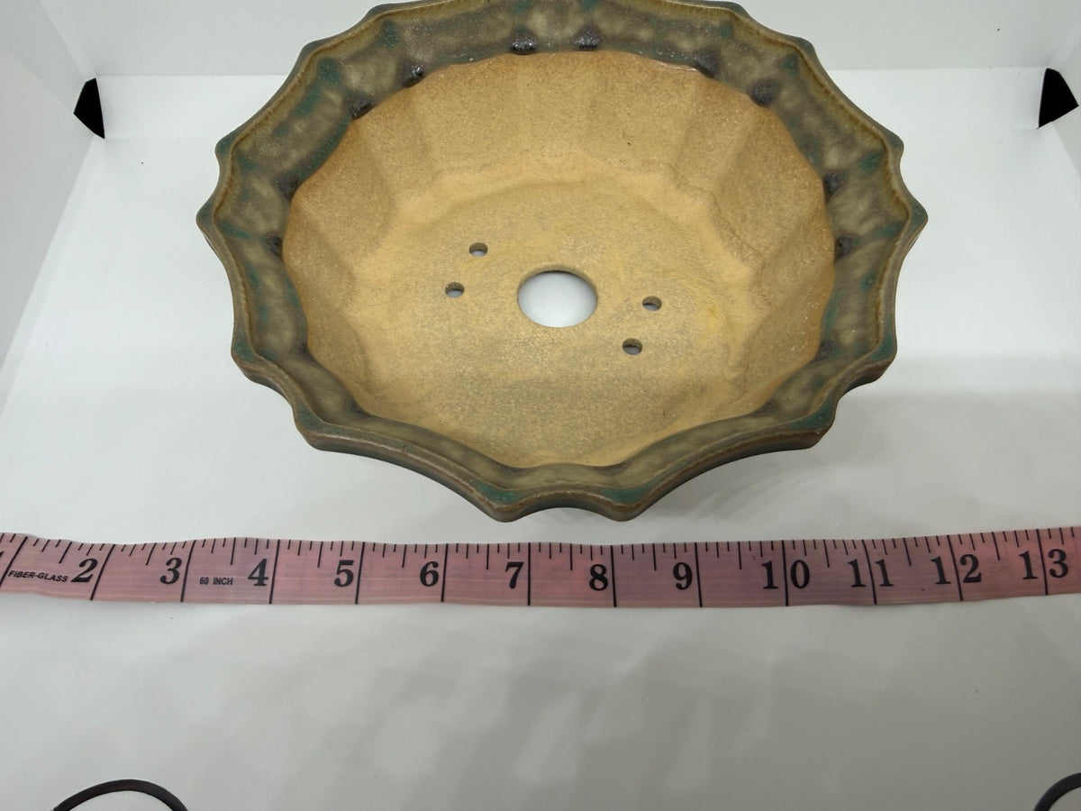 Overhead view of the green flower pot's pale interior with one central drainage hole and four smaller openings