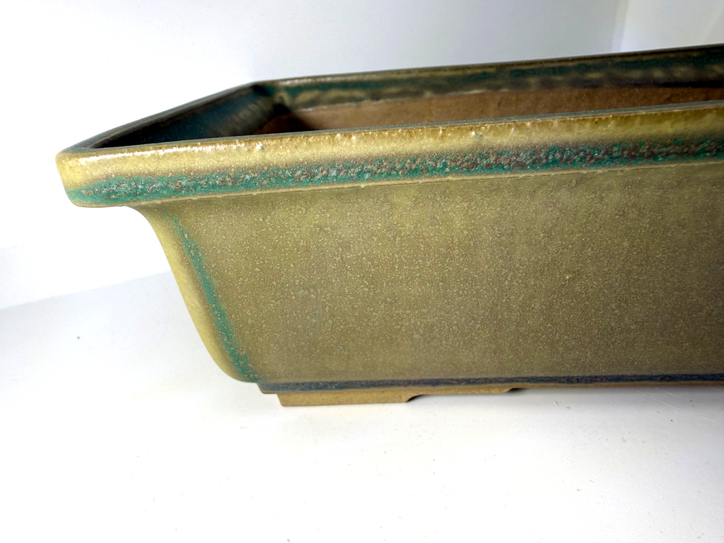 Close-up of the green rectangular pot's flared rim, corner and glazed side wall