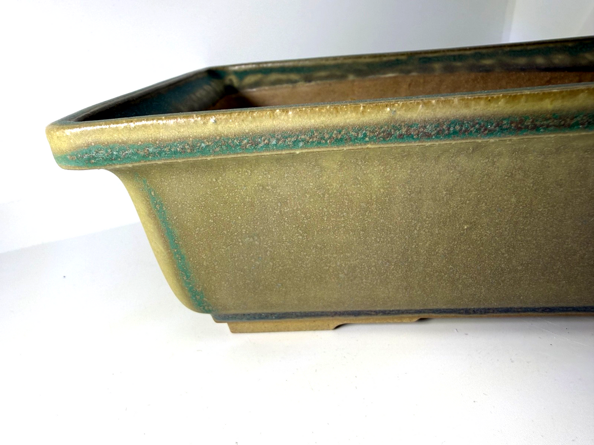 Close-up of the green rectangular pot's flared rim, corner and glazed side wall