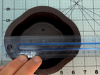 Ruler across the length of the brown oval pot's lobed interior opening