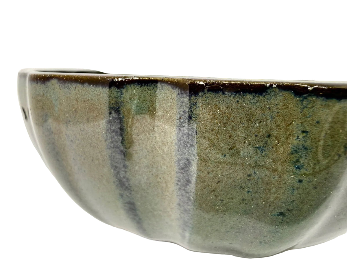 Close-up of the green-gray pot's curved fluted wall and dark glaze streaks