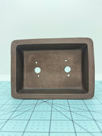 Interior of the dark brown rectangular pot showing two drainage holes and four smaller openings