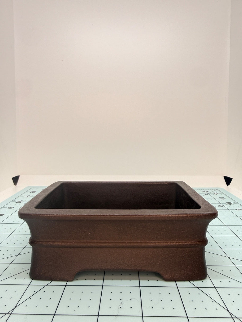 Front view of the dark brown pot showing its raised horizontal band and cutout below the base
