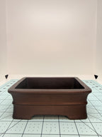 Front view of the dark brown pot showing its raised horizontal band and cutout below the base