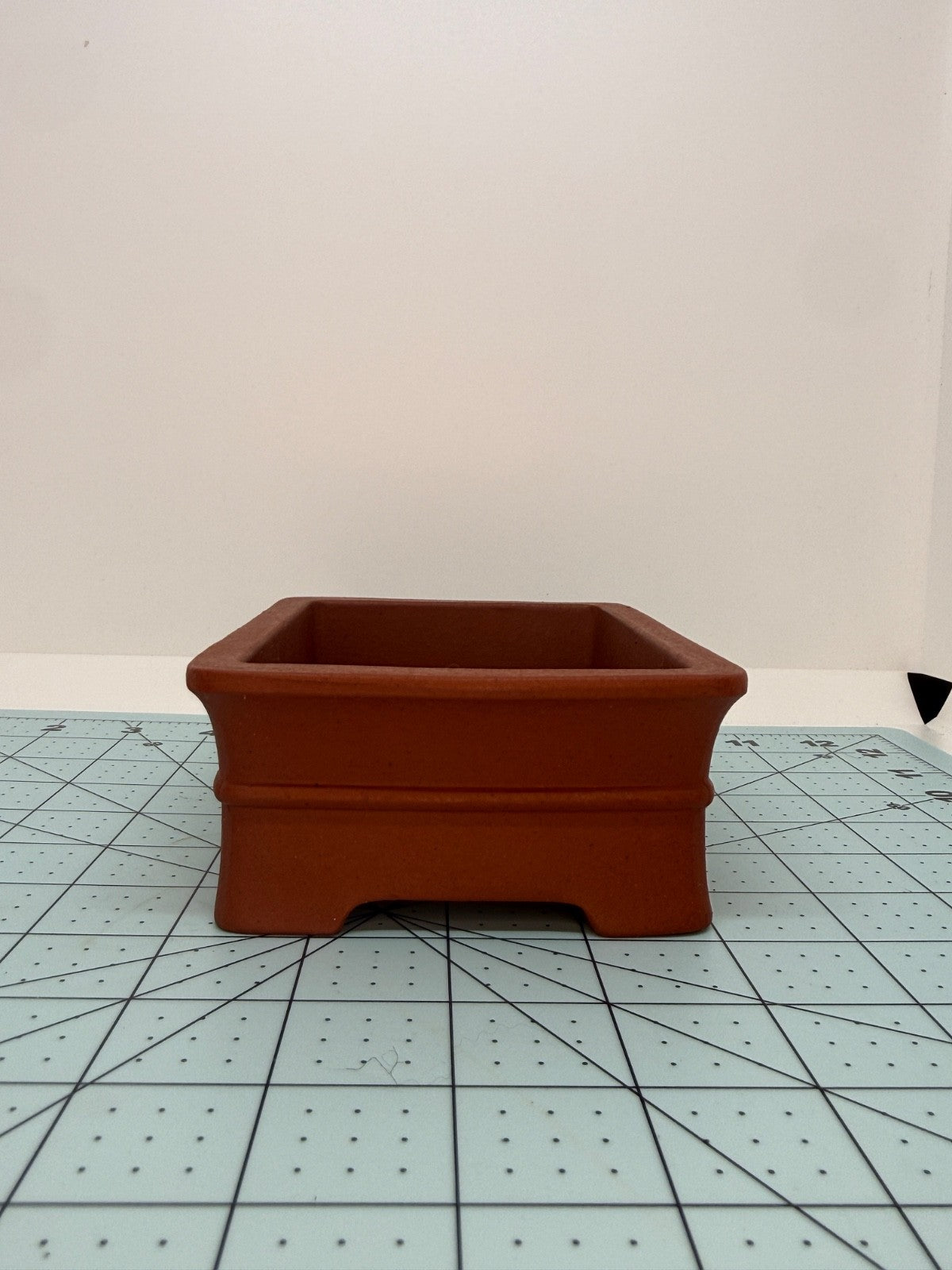 Short-side view of the red pot showing its flared rim and cutout between the feet