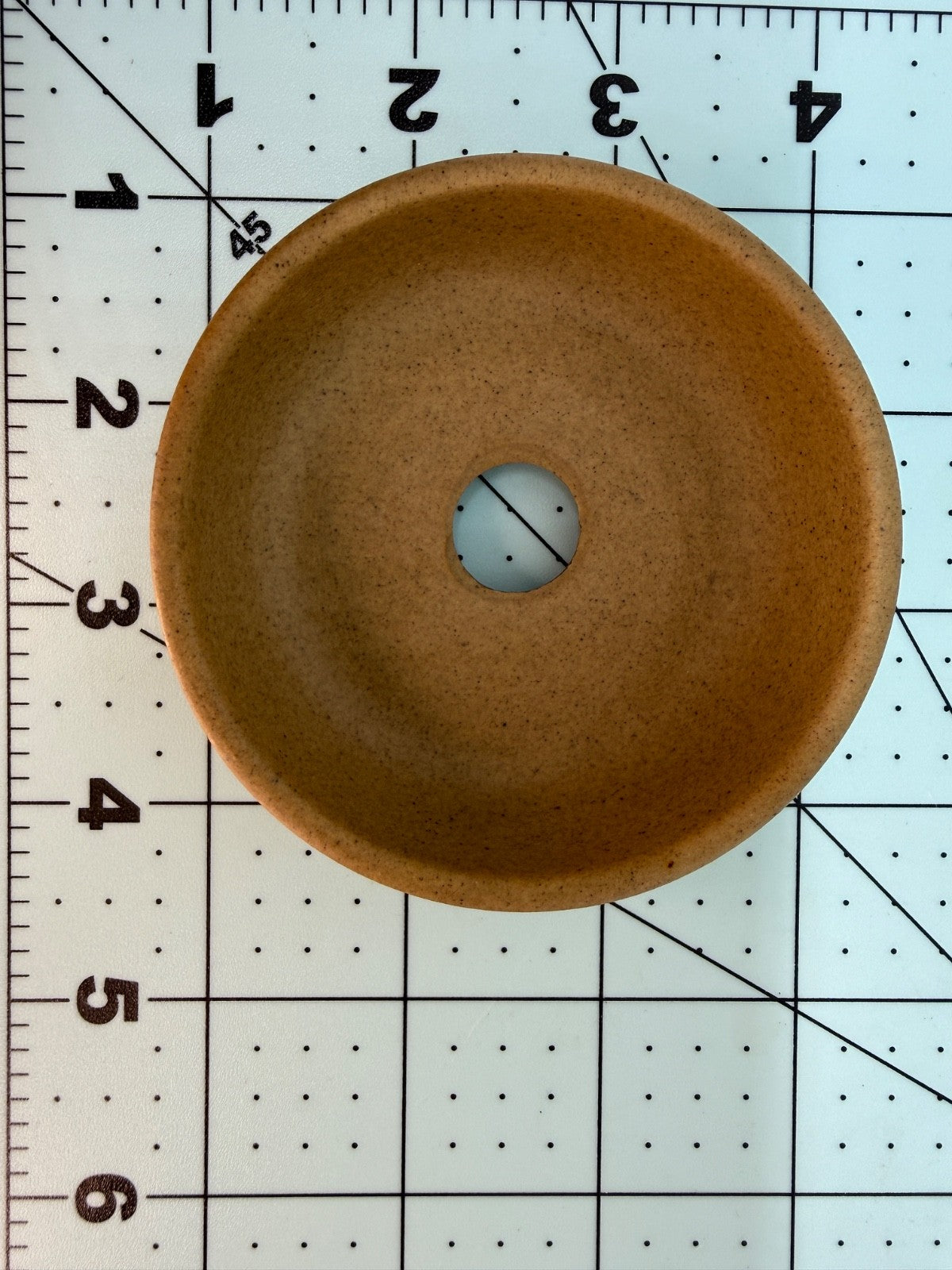 Overhead interior view of the ochre pot with one central drainage hole on a measuring grid