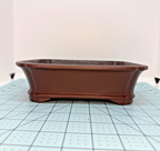 Long-side view of the brown rectangular pot with banded base and shaped feet