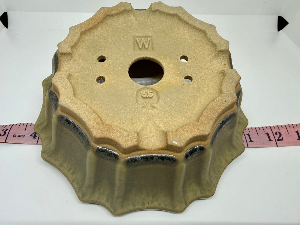 Underside of the flower-shaped pot showing drainage holes, an impressed W mark and a 6.5 mark