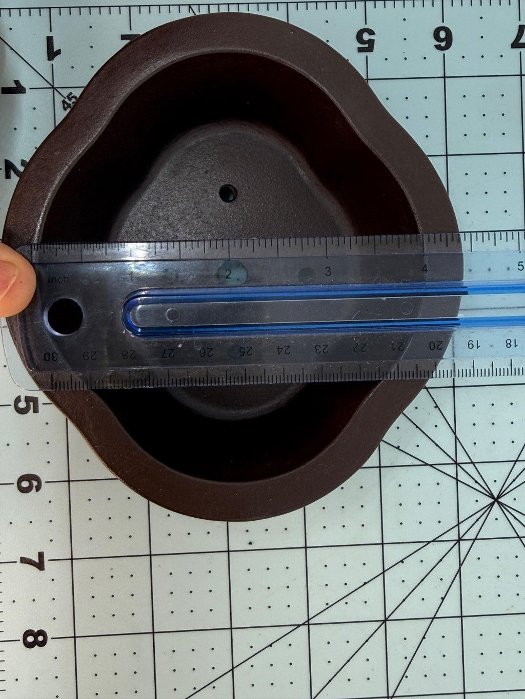 Ruler across the width of the brown oval pot's interior