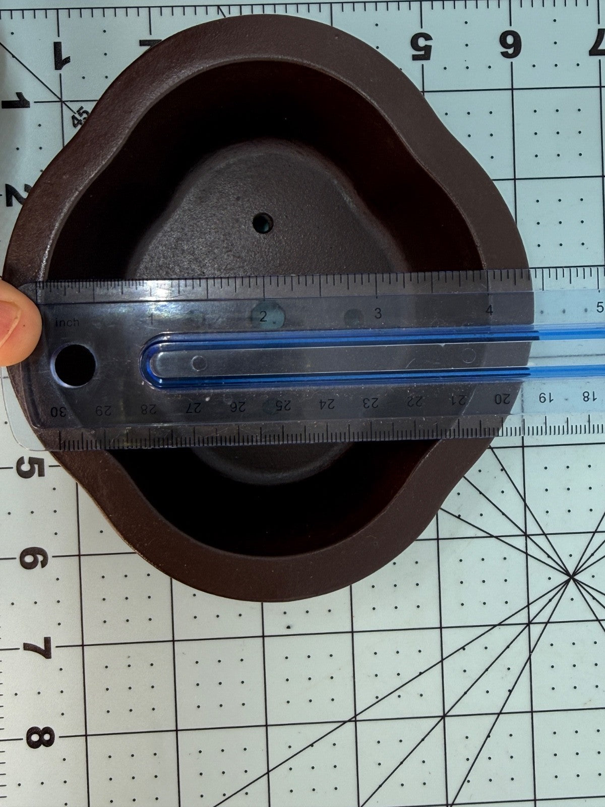 Ruler across the width of the brown oval pot's interior