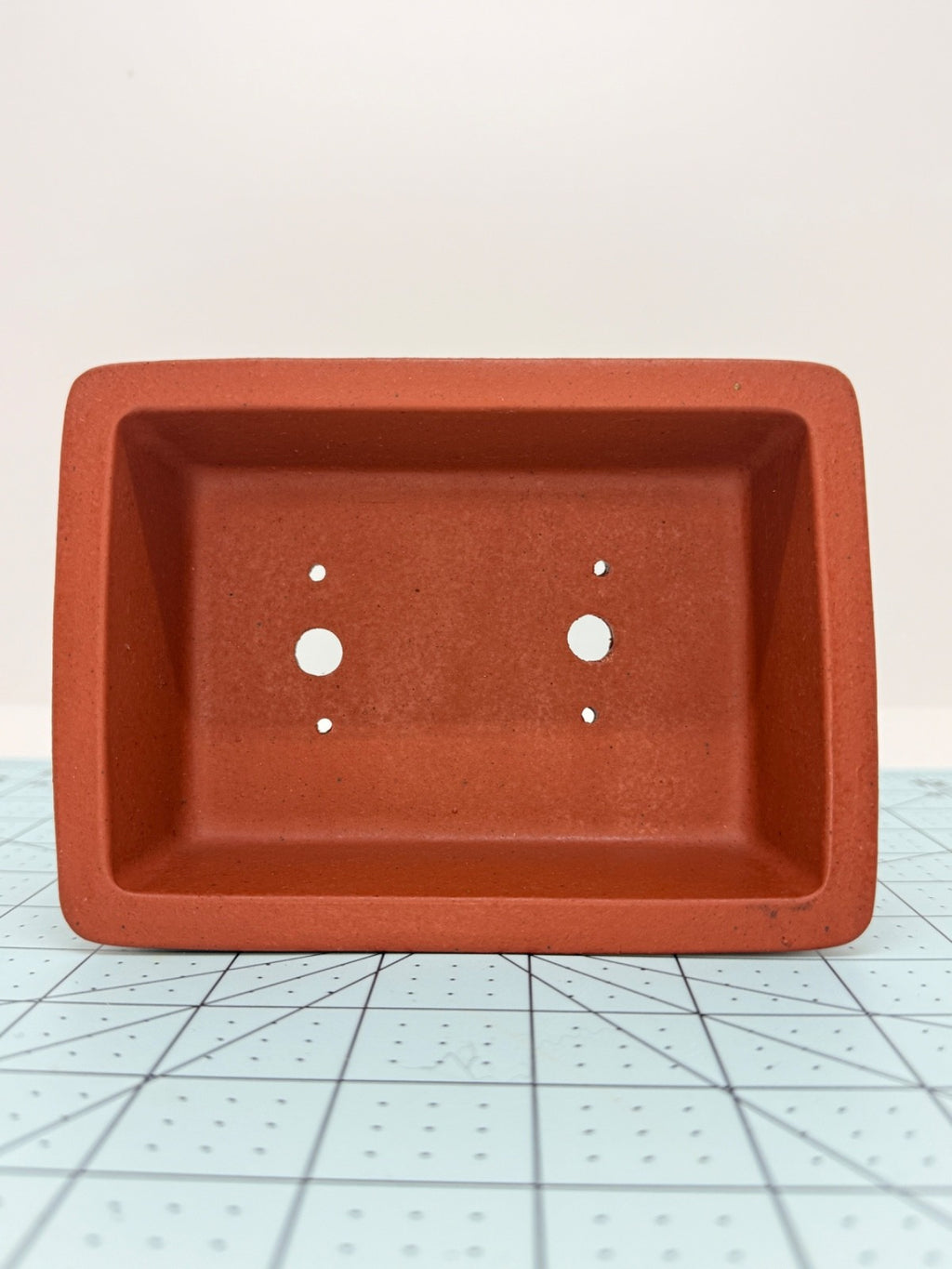 Top view of the red rectangular bonsai pot showing its interior and drainage openings