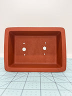 Top view of the red rectangular bonsai pot showing its interior and drainage openings