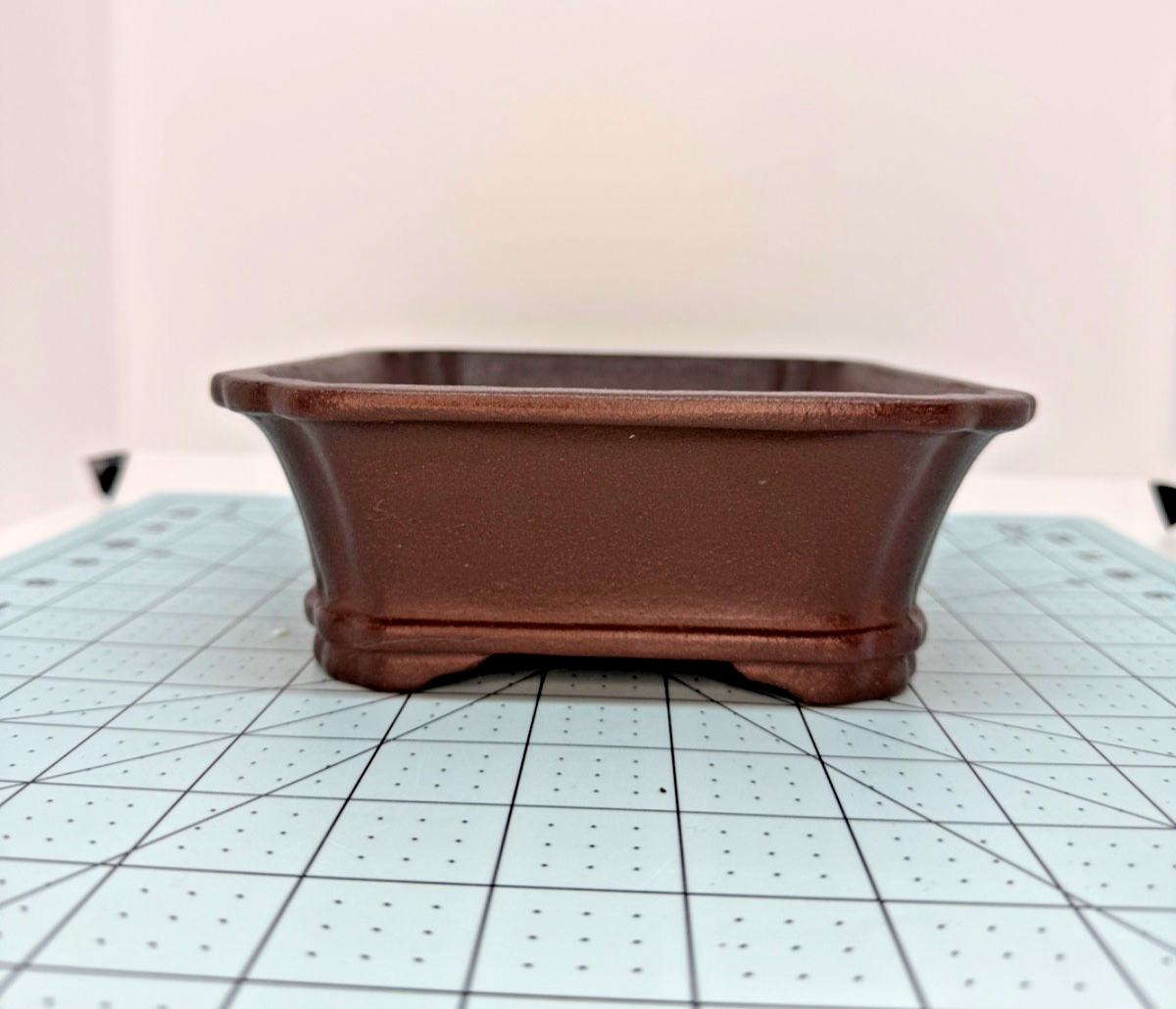 Opposite short-side view of the brown pot on a gridded mat
