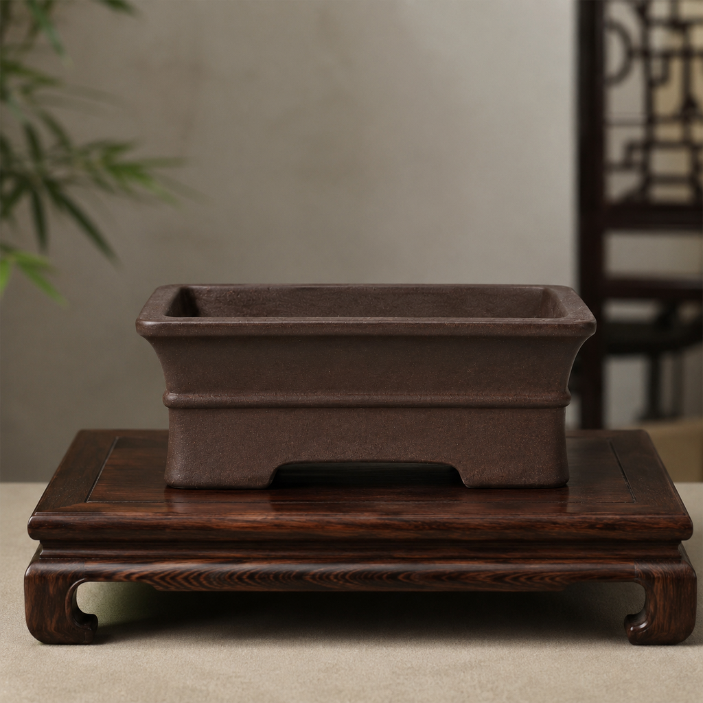 Dark brown rectangular bonsai pot displayed on a carved wooden stand
