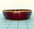 Low front view of the round pot with plum-colored glaze and fine crackle texture