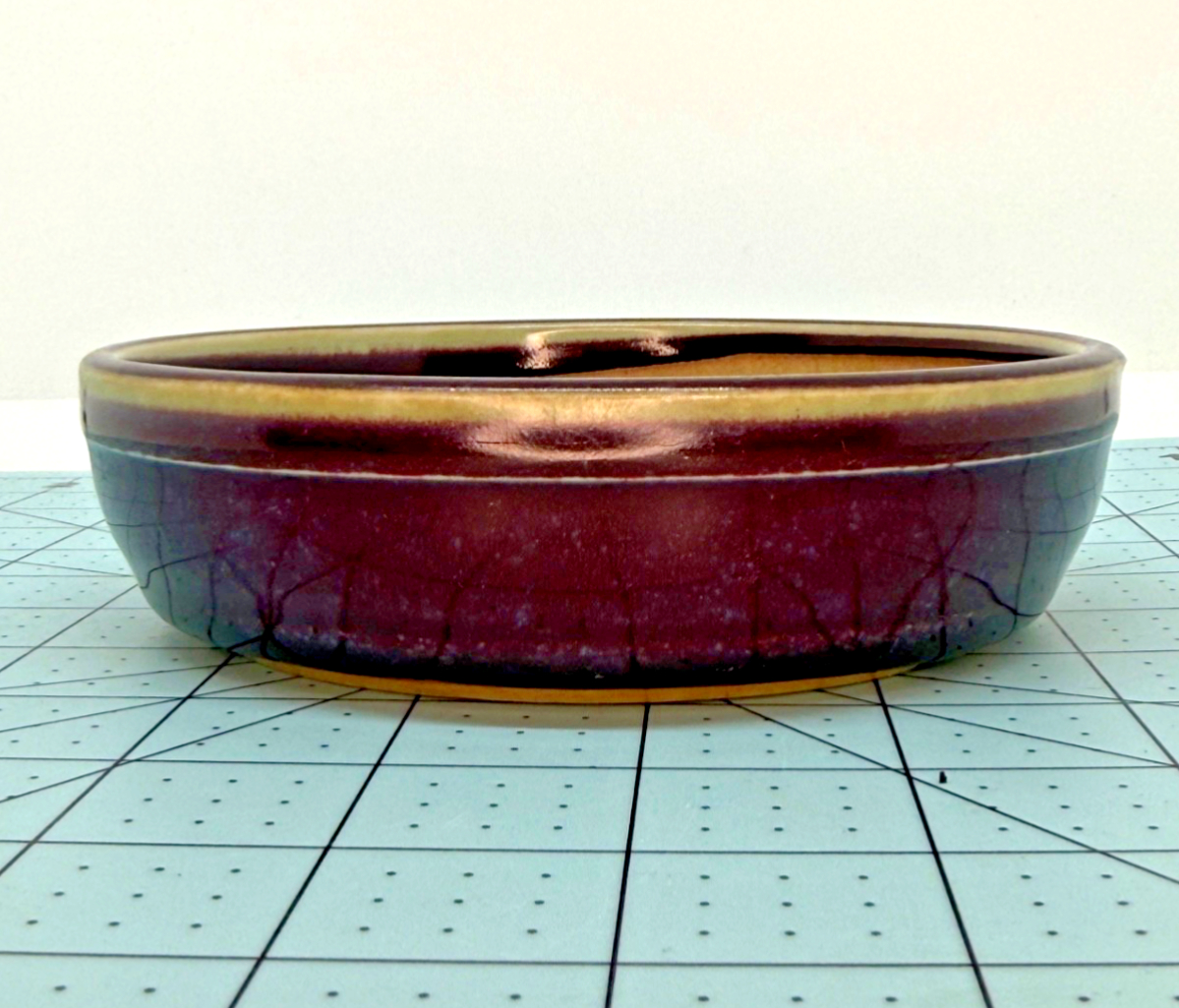 Low front view of the round pot with plum-colored glaze and fine crackle texture