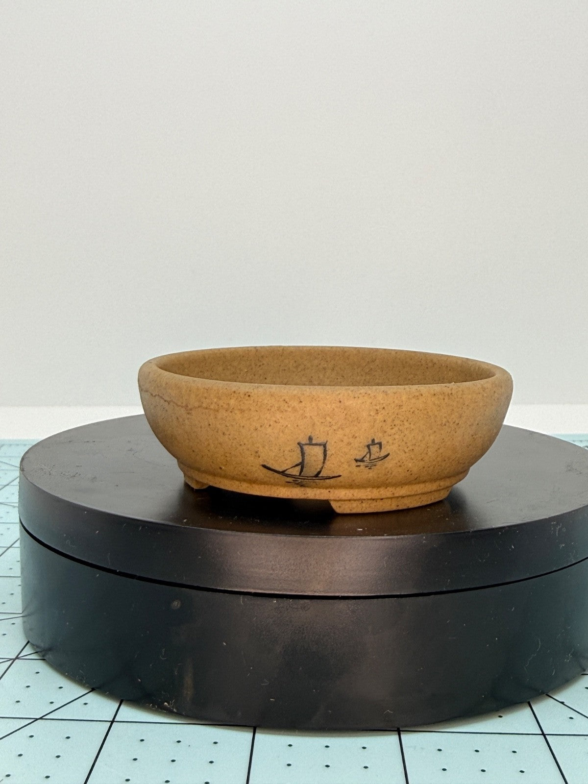Ochre oval pot with boat decoration displayed on a black turntable
