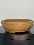 Ochre oval pot showing a fine landscape line across its speckled side
