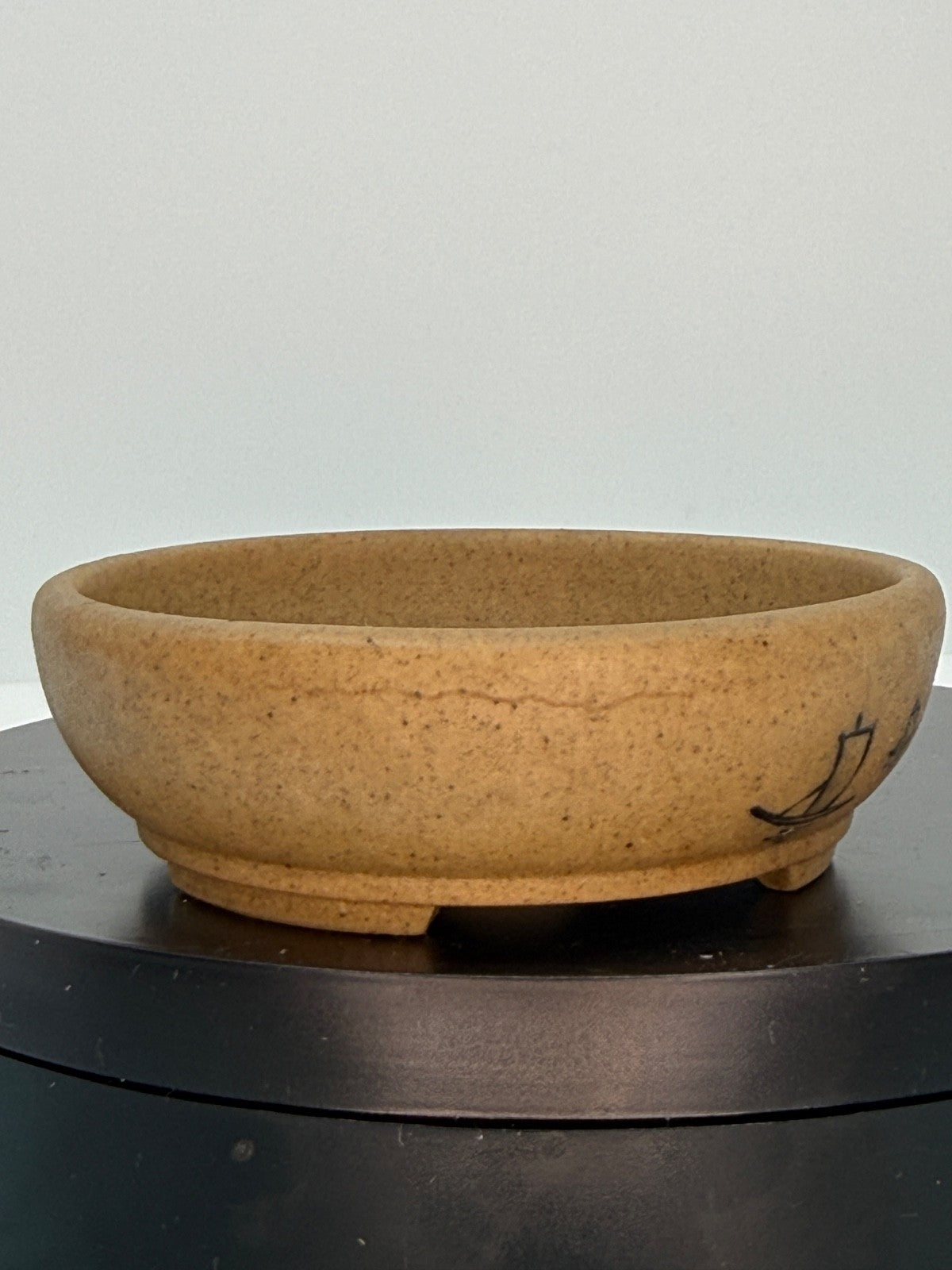 Ochre oval pot showing a fine landscape line across its speckled side